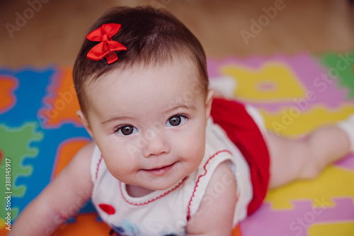 Close-up of cute smiling baby girl lying on puzzle playmat at home photo