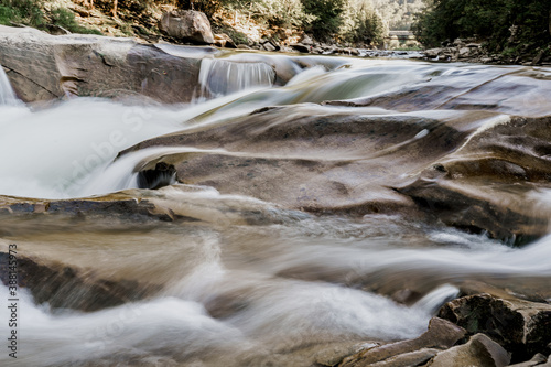 Waterfall with blurry water because it was photographed at long shutter speed. Waterfall in the mountain river with big rocks. Travelling in quarantine period. Nature landscape. Karpathians mountains photo