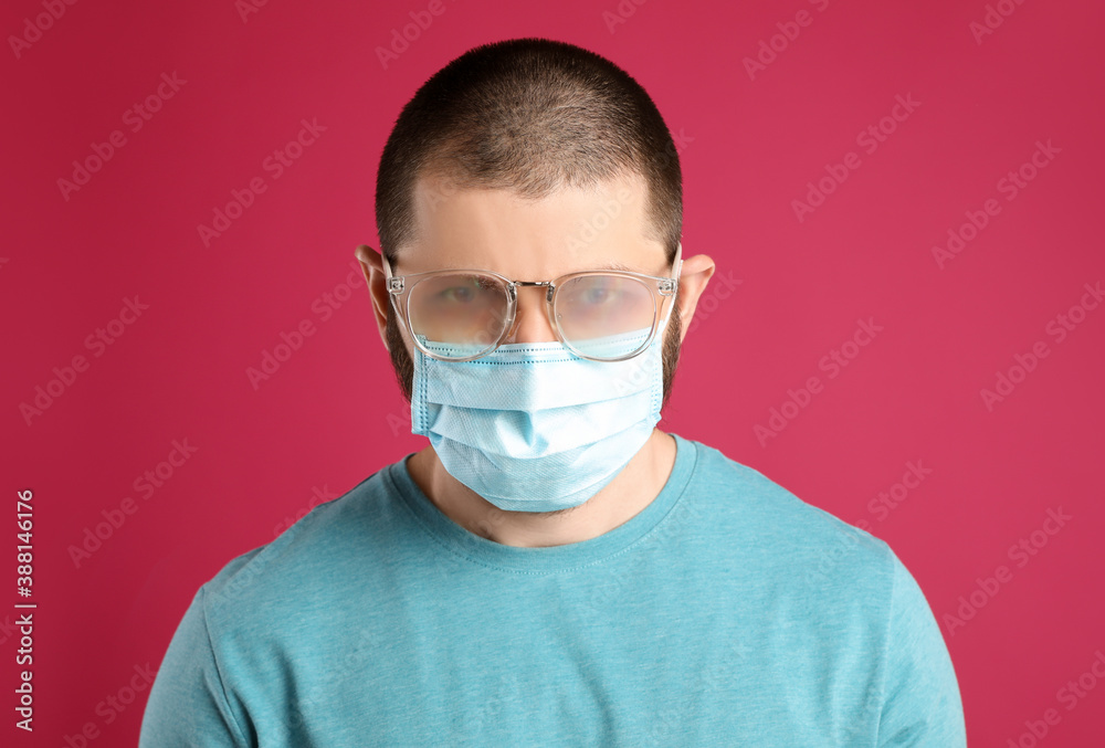 Man with foggy glasses caused by wearing disposable mask on pink background. Protective measure during coronavirus pandemic Man with foggy glasses caused by wearing disposable mask on pink background. Protective measure during coronavirus pandemic
