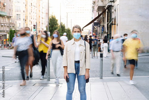 Young woman wearing mask standing on street in city photo