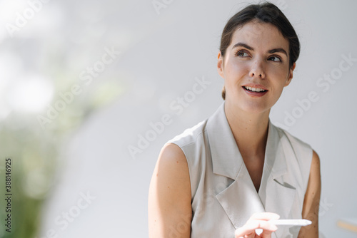 Thoughtful woman looking away while holding digitized pen at office photo