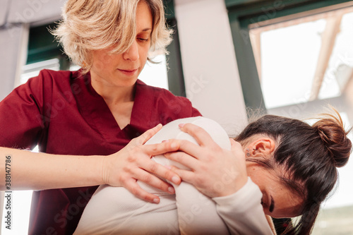 Physiotherapist massaging back of woman sitting with arms crossed photo