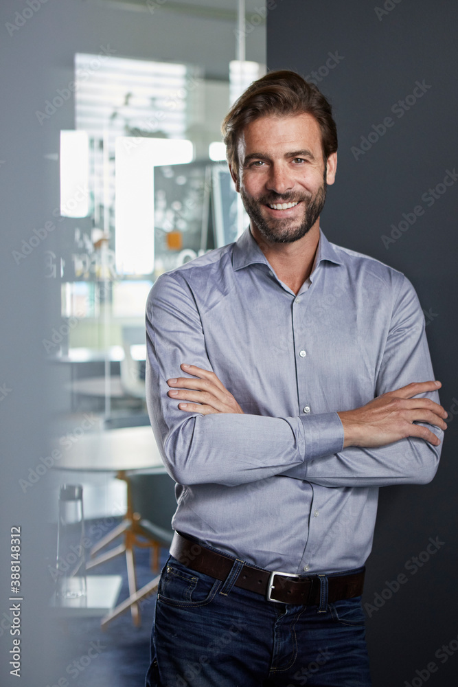 Confident businessman standing with arms crossed in office
