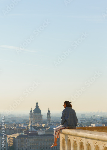 Girl watching the beautiful panoramic landscape and skyline of the city of Budapest from a high building. Holidays background in summer 