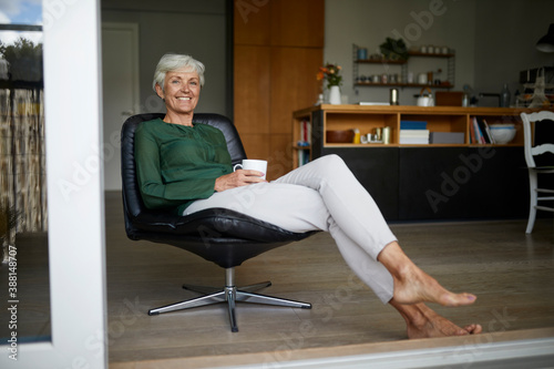 Senior woman spending leisure time while drinking coffee at home