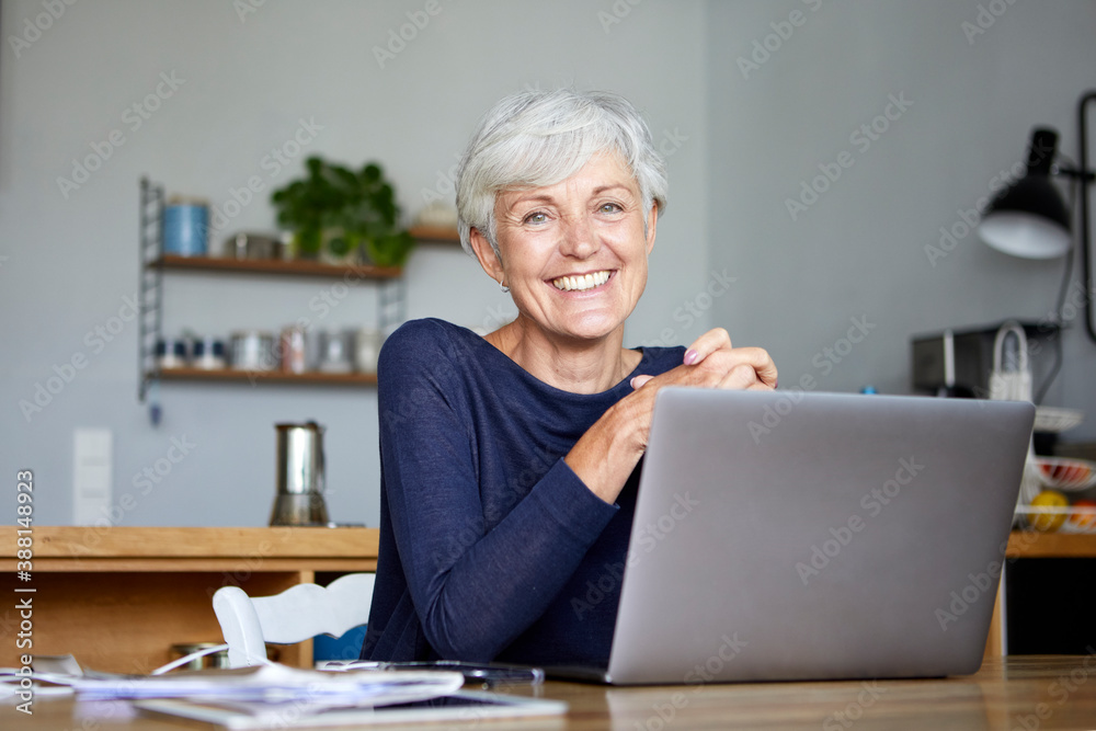 Smiling active senior using laptop while sitting at home Smiling active senior using laptop while sitting at home
