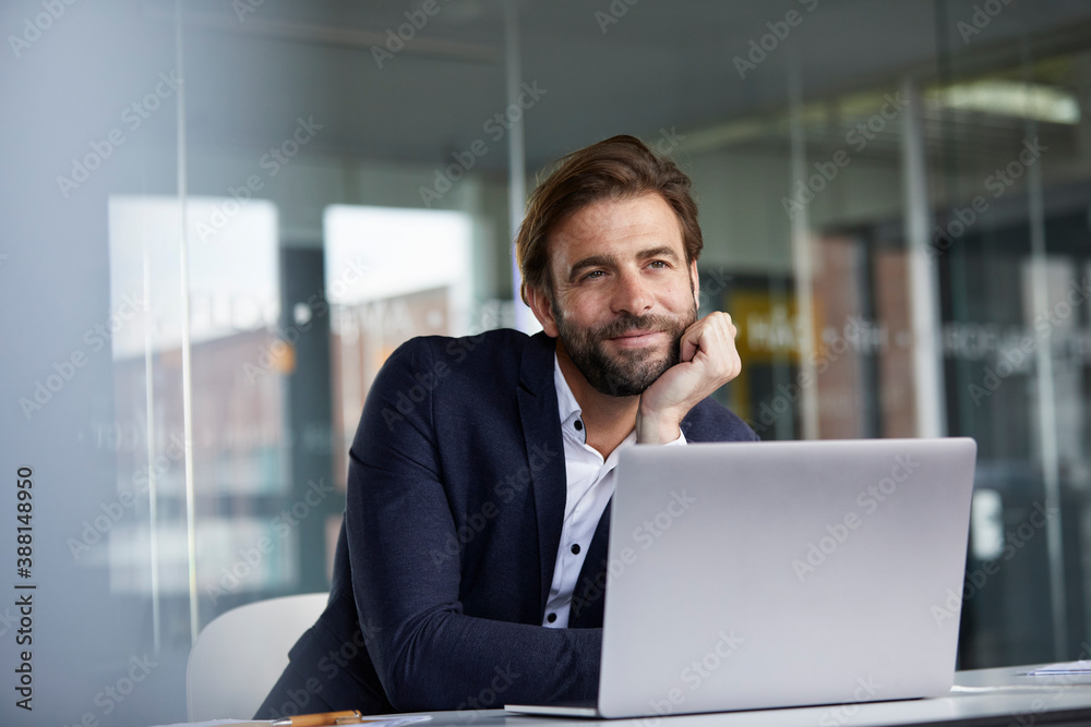 Businessman with head in hands leaning on desk while sitting in office Businessman with head in hands leaning on desk while sitting in office