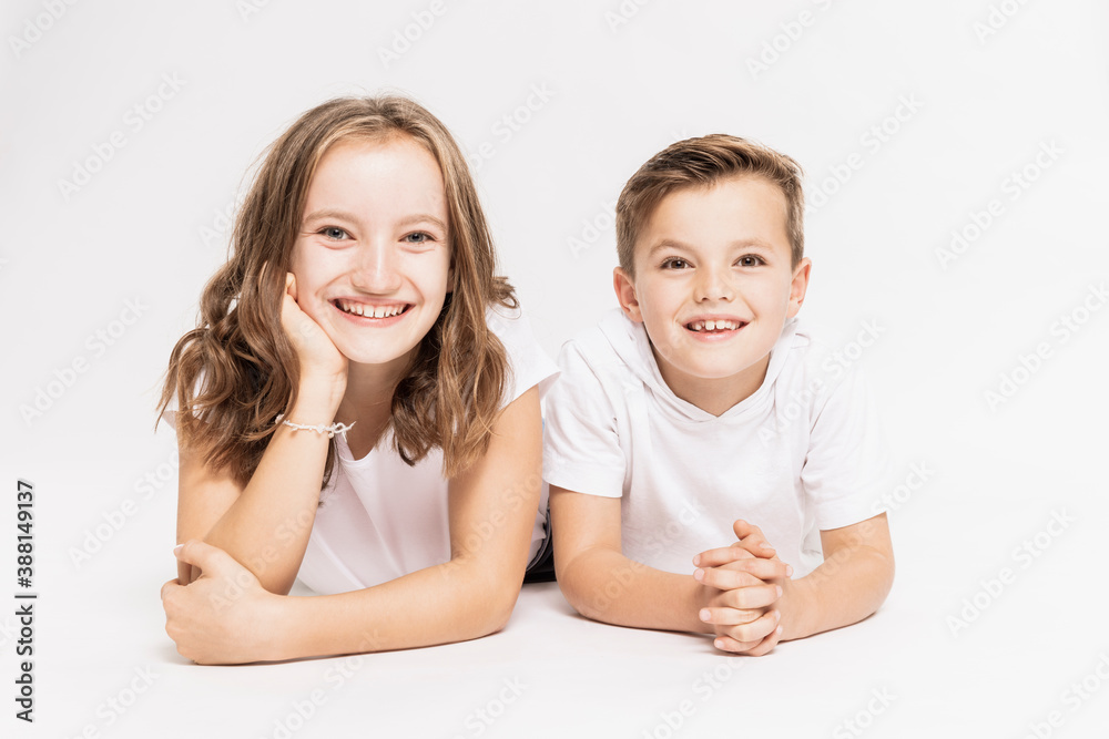 Cute smiling siblings lying on white background Cute smiling siblings lying on white background