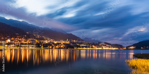 Switzerland, Canton of Grisons, Saint Moritz, panorama of Lake Saint Moritz and illuminated town in Engadine valley at dusk