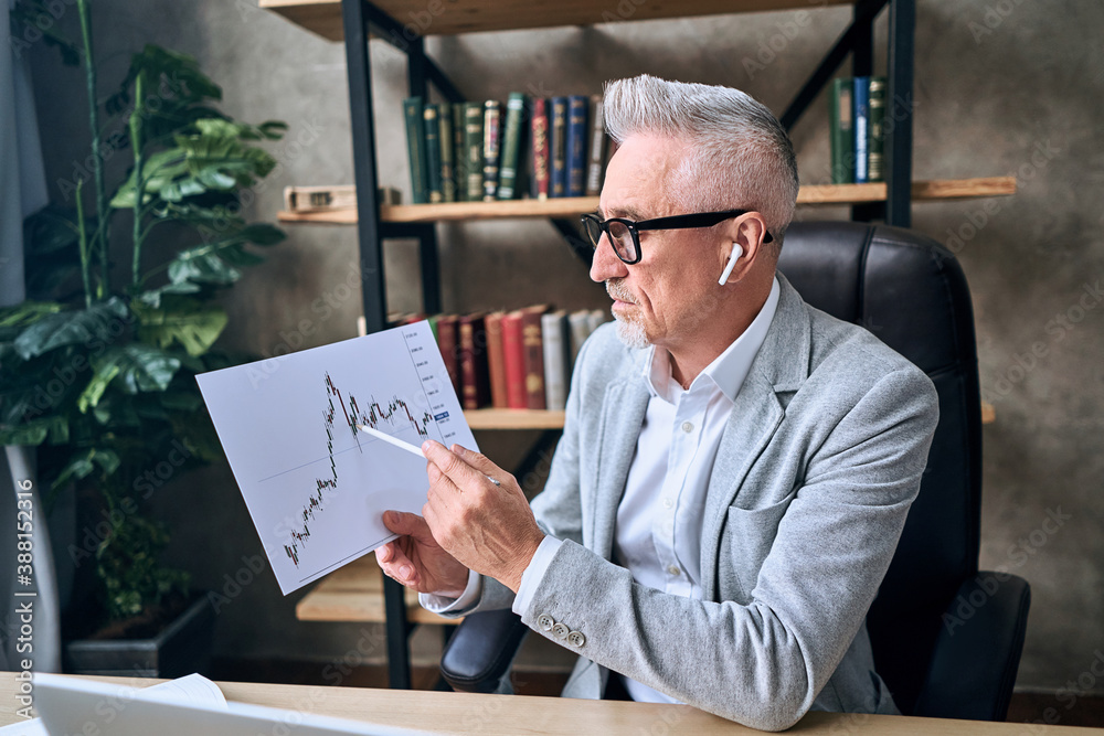 Adult man holding report and pen and discussing the results of work during an online meeting Adult man holding report and pen and discussing the results of work during an online meeting