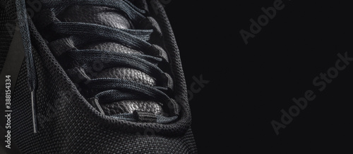 Black sneaker shoe on a black background. Closeup photo