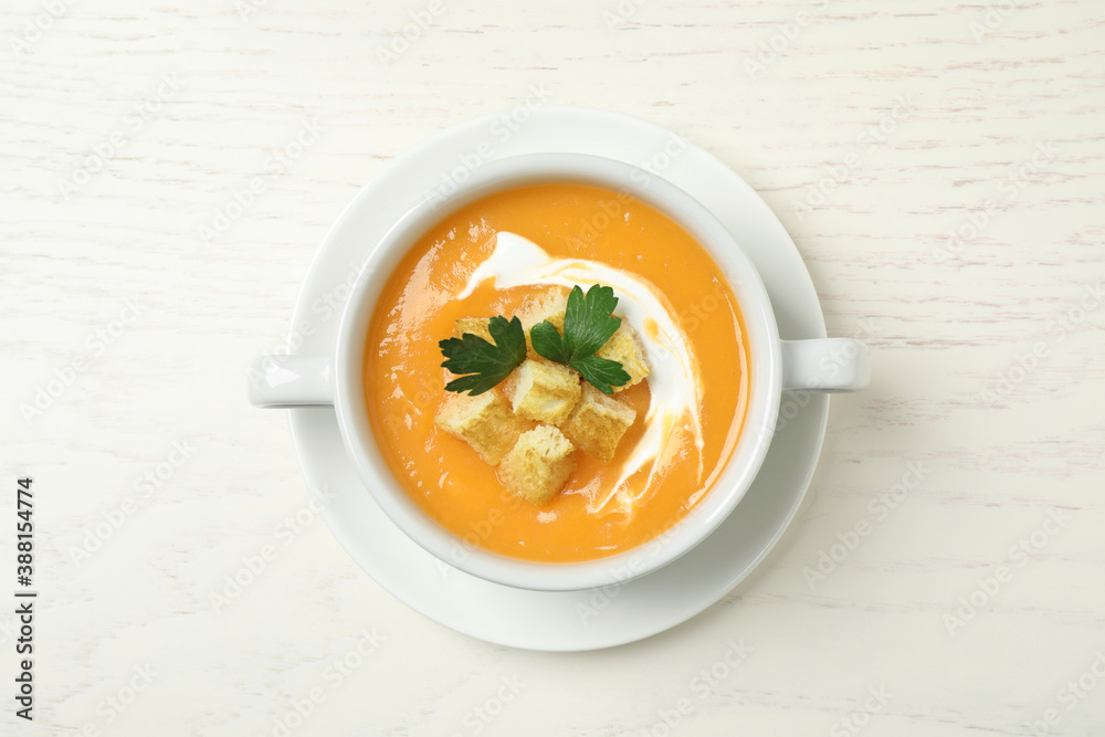 Delicious pumpkin soup in bowl on white wooden table, top view Delicious pumpkin soup in bowl on white wooden table, top view