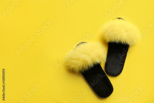 Pair of soft slippers on yellow background, flat lay. Space for text