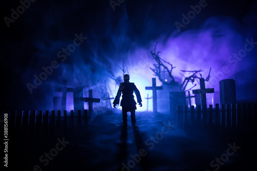 Scary view of zombies at cemetery dead tree, moon, church and spooky cloudy sky with fog, Horror Halloween concept with glowing pumpkin. Selective focus