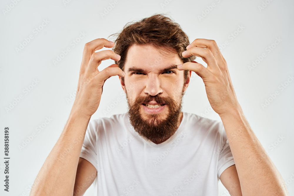Bearded man gesturing with hands cropped view white t-shirt studio emotion light background