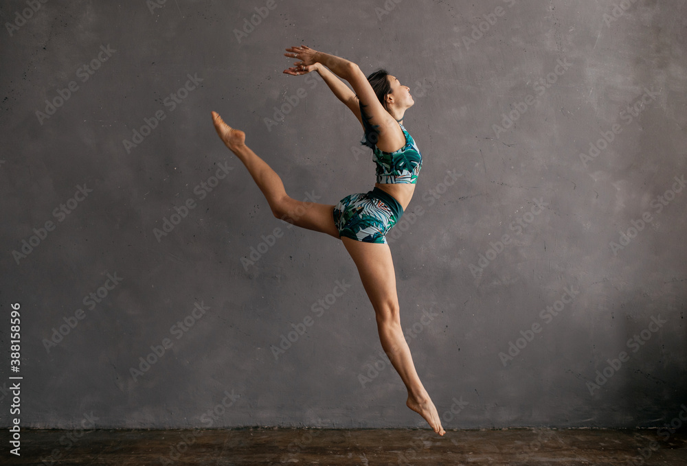Graceful gymnast jumping against weathered wall Graceful gymnast jumping against weathered wall