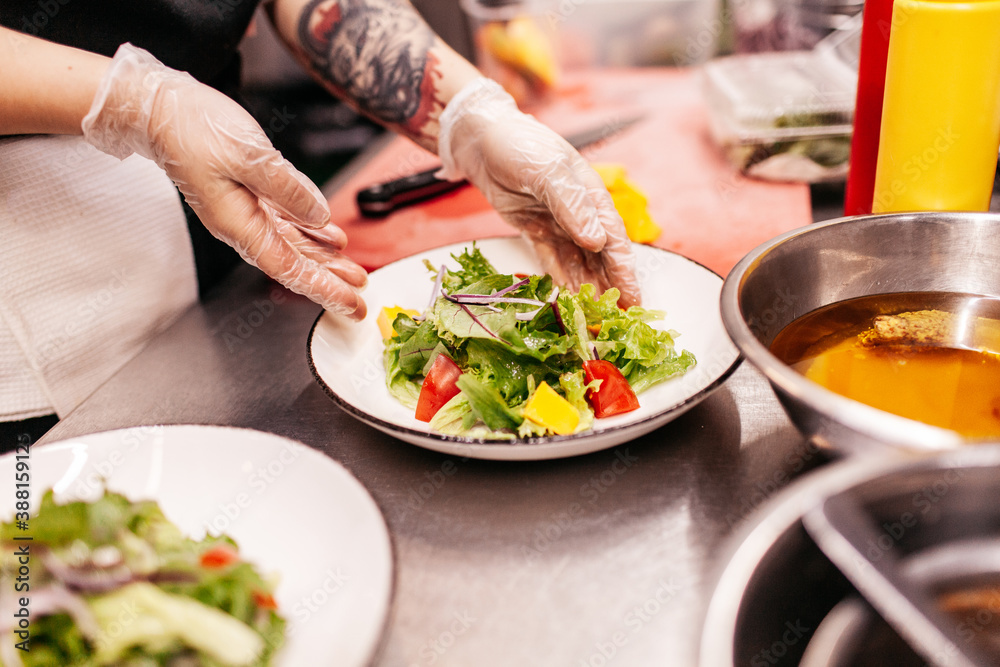 Unrecognizable female chef serving salad in kitchen Unrecognizable female chef serving salad in kitchen