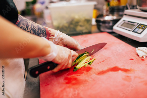 Unrecognizable cook chopping vegetable in kitchen