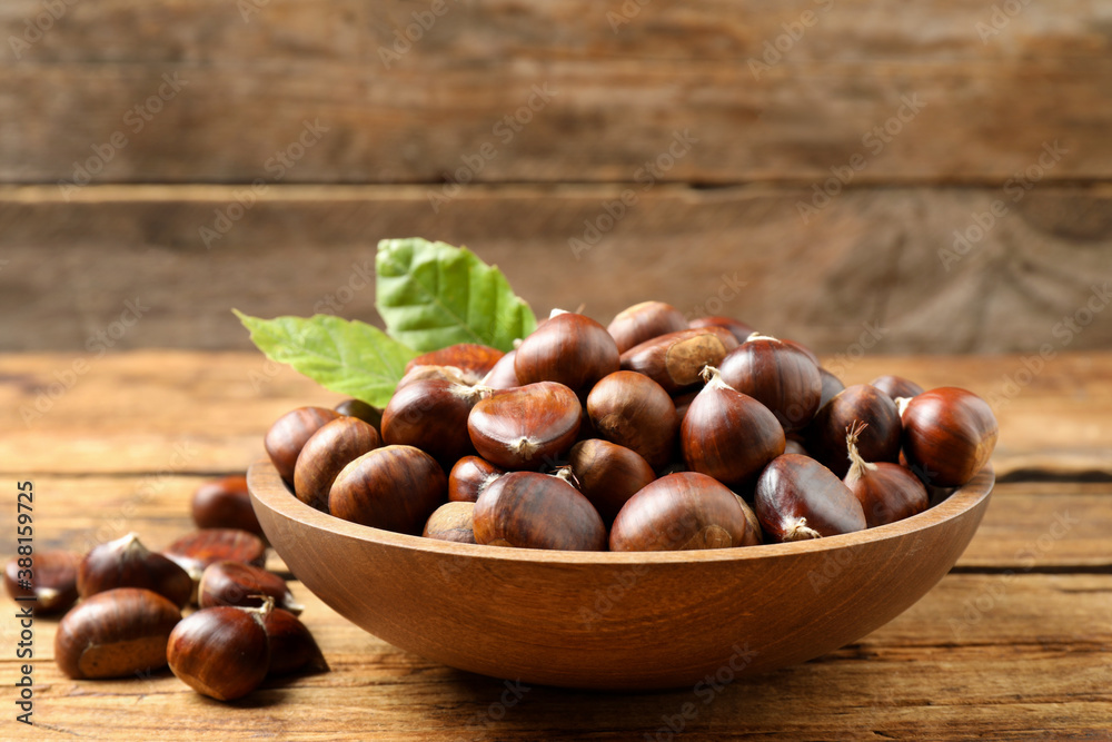 Fresh sweet edible chestnuts in bowl on wooden table Fresh sweet edible chestnuts in bowl on wooden table