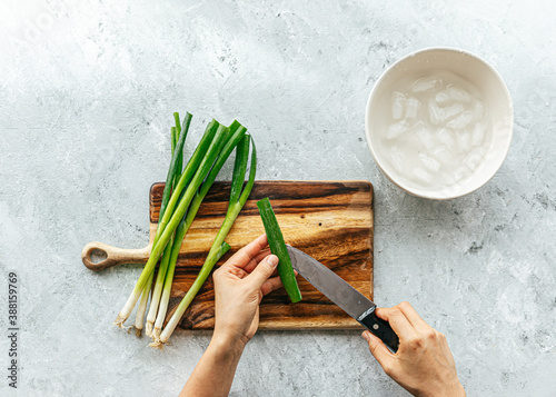 Overhead shot of hand slicing green onions for garnish