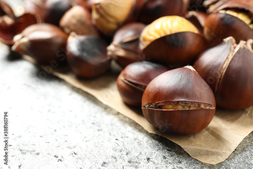 Delicious roasted edible chestnuts on grey table, closeup