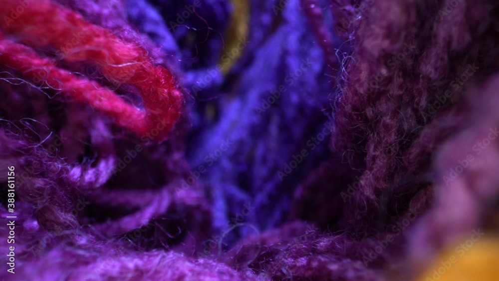 The multi colored wool yarn is close up to show the detailed texture. Vertically sliding camera moving along a bright rainbow yarn. Dolly super macro shot.