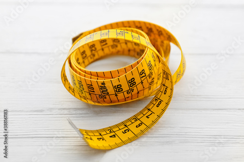 Yellow measuring tape on white wooden table, closeup