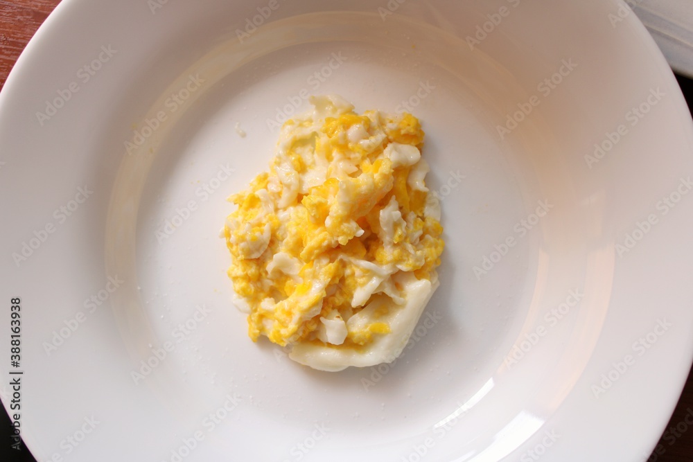round white plate with scrambled eggs inside for early morning breakfast
