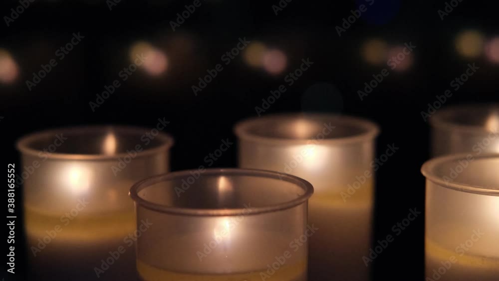 many candles mysteriously burn in front of the window in complete darkness, blurred reflections and lights of lamps in the glass, the concept of religion, faith, mourning for the dead many candles mysteriously burn in front of the window in complete darkness, blurred reflections and lights of lamps in the glass, the concept of religion, faith, mourning for the dead