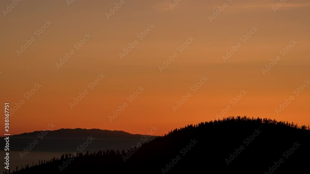 Blissful moment of sun going down behind silhouette of mountainous forest Blissful moment of sun going down behind silhouette of mountainous forest