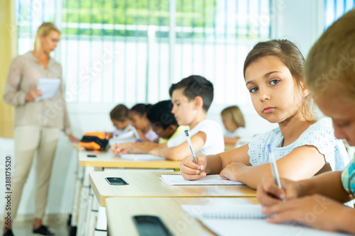 Portrait of focused tween schoolgirl sitting on lesson in classroom, looking confidently at camera © JackF