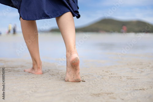 Woman barefoot walking on the beach at  summer along wave of sea water and sand. © Charnchai saeheng