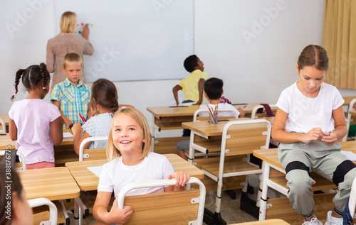 Tween boys and girls friendly talking in break between lessons sitting in classroom