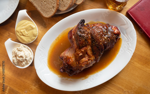 Top view of baked pork knuckle traditionally served in gravy with horseradish, mustard and fresh bread. Traditional czech cuisine
