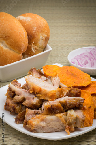 Procion de chicharron de cerdo, camote frito, cebolla y pan photo