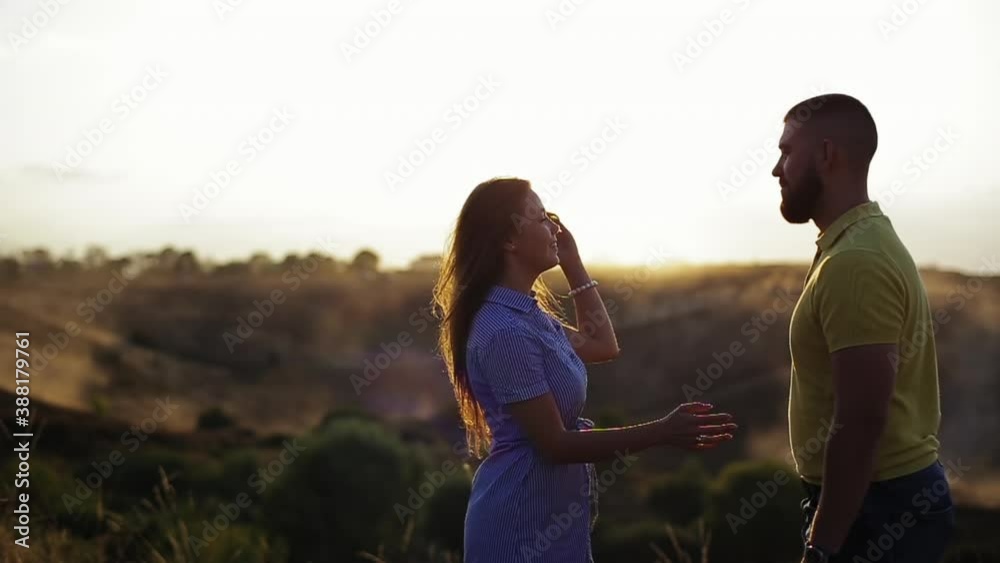 Medium view of young couple in love with bearded guy and beautiful girl hugging and kissing in deserted background in the evening, background of sunset in slow motion. Romantic date in nature together Medium view of young couple in love with bearded guy and beautiful girl hugging and kissing in deserted background in the evening, background of sunset in slow motion. Romantic date in nature together