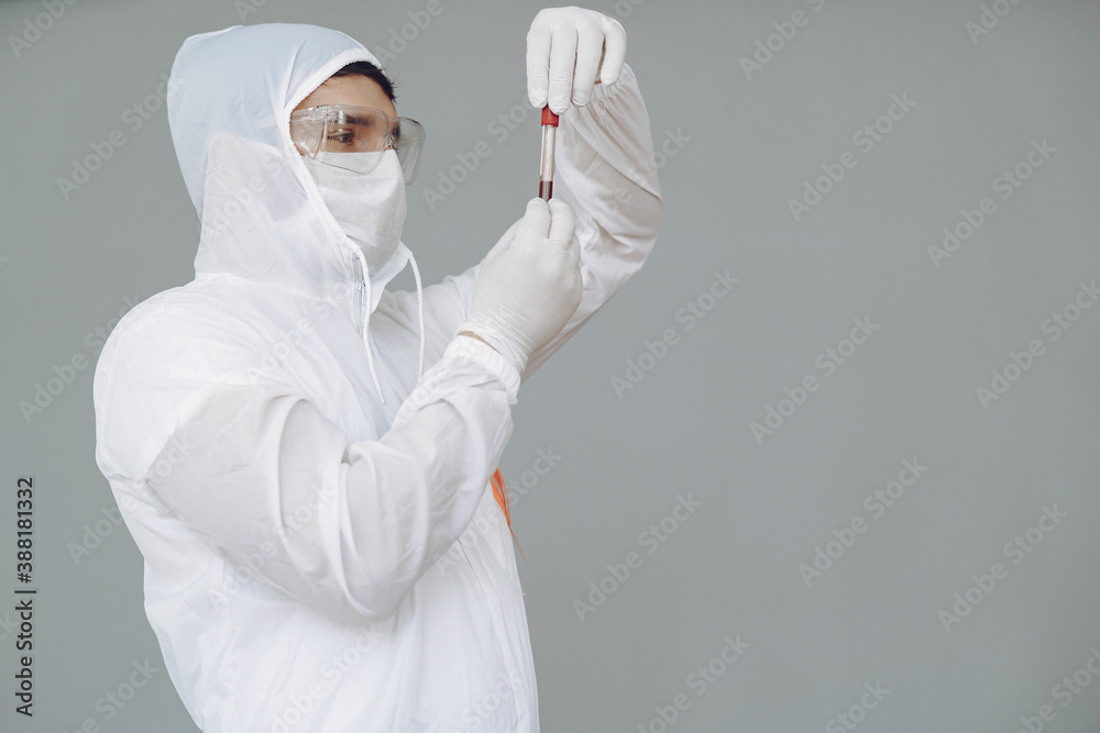 Corona virus theme. Man in a protective suit. Doctor looks at the blood tube.