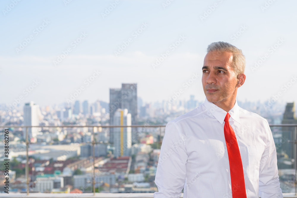 Handsome Persian businessman thinking against view of the city Handsome Persian businessman thinking against view of the city