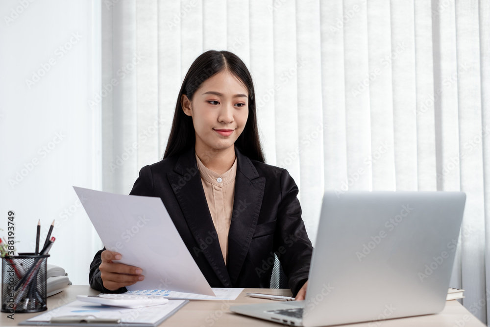 Asian businesswomen sit at their desks and calculate financial graphs showing results about their investments, plan a successful business growth process in the office Asian businesswomen sit at their desks and calculate financial graphs showing results about their investments, plan a successful business growth process in the office