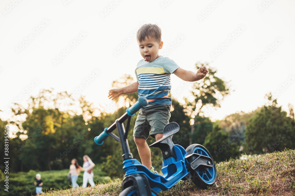 Cute caucasian boy is playing with a bike outside in a park on a green field celebrating children day Cute caucasian boy is playing with a bike outside in a park on a green field celebrating children day