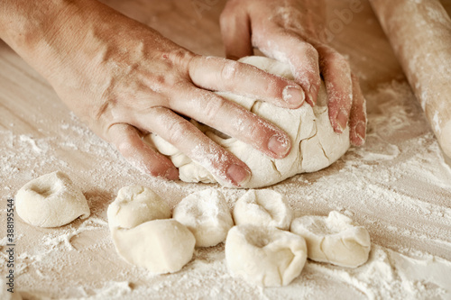 woman chef kneads the dough with her hands, female hands in flour, female chef holds the dough with her hands, female hands with dough