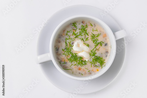 Creme soup with mushrooms in white bowl served over white background. Delicious vegetable soup for dinner.