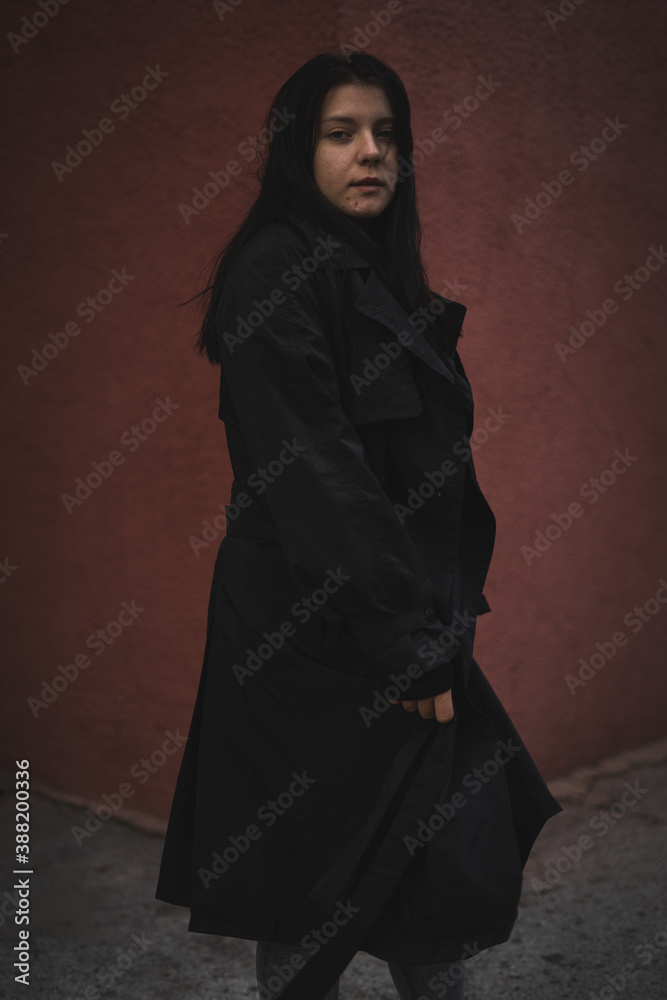 A girl in a black cloak on a red background.