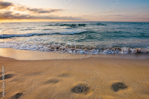 sunrise at the sea. beautiful summer landscape on the sandy beach. green waves rush on the shore in golden light