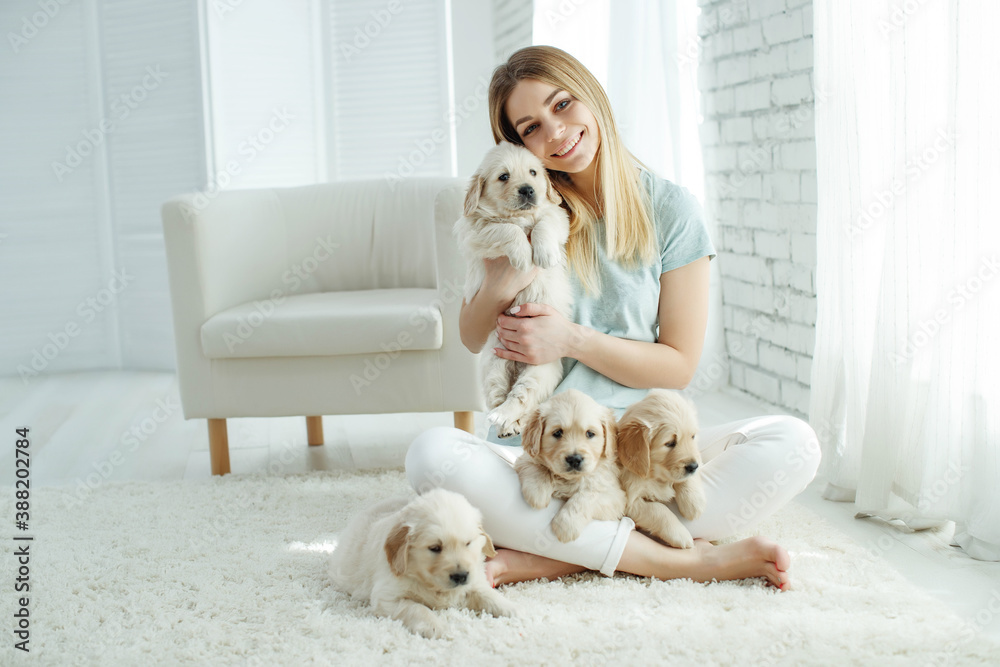 Cute young woman kisses and hugs a Labrador Retriever puppy dog. Love between owner and dog. In the room at home, interior. High quality photo. Cute young woman kisses and hugs a Labrador Retriever puppy dog. Love between owner and dog. In the room at home, interior. High quality photo.