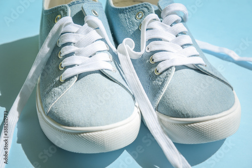 Blue sneakers with white laces on a light blue background. Trendy fashionable casual concept.