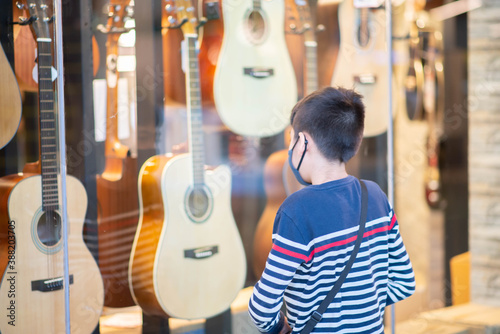 Little boy standing in front of guitar shop supermarket