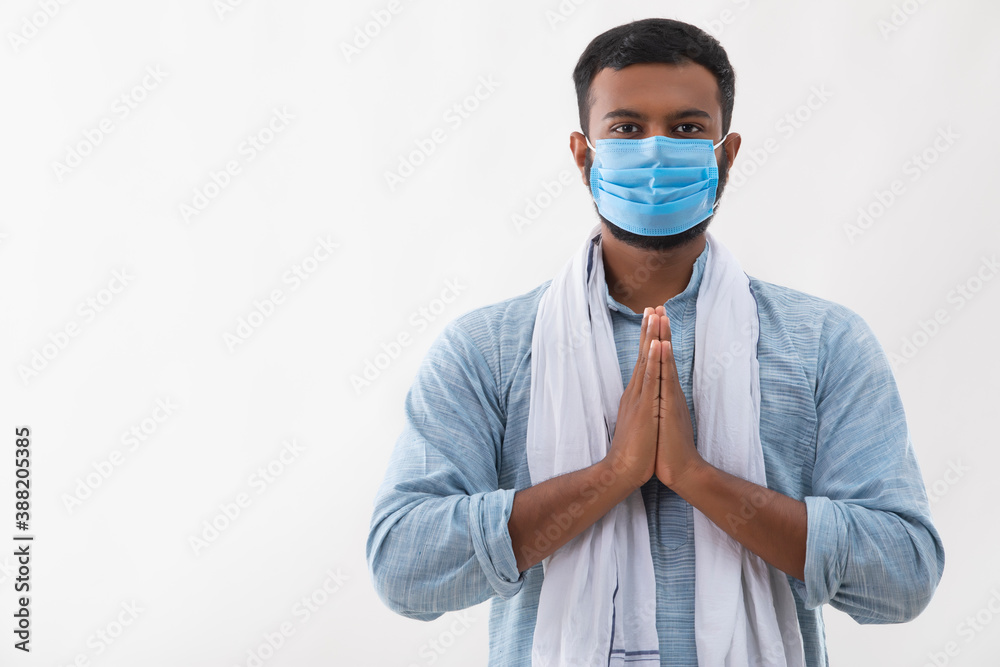 PORTRAIT OF A RURAL MAN WEARING MASK WITH FOLDED HANDS IN GREETING
PORTRAIT OF A RURAL MAN WEARING MASK WITH FOLDED HANDS IN GREETING