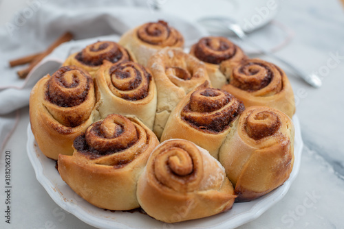 Cinnamon rolls with sugar frosting. With cinnamon sticks and spices, wooden background