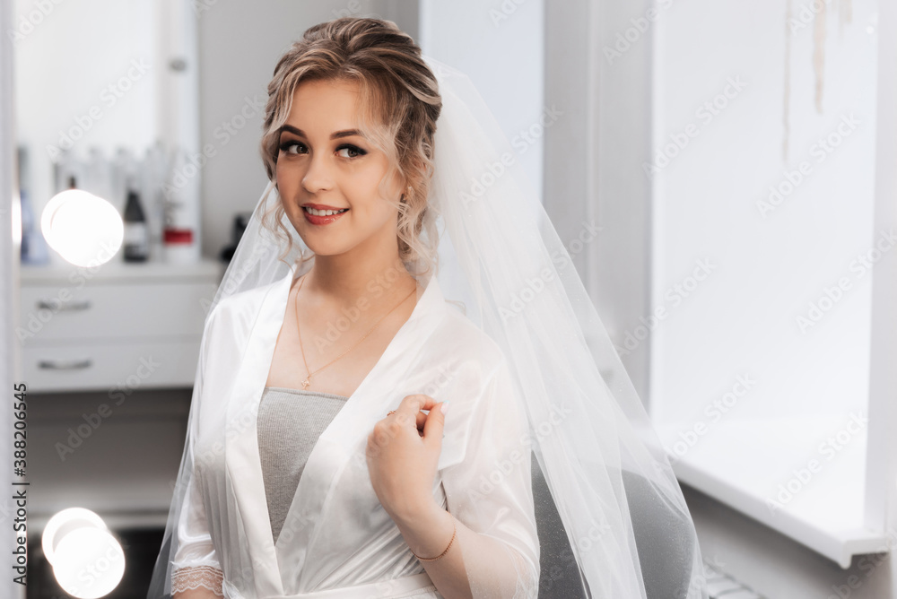 portrait of a bride in a beauty salon, beautiful blonde with hair and makeup in a veil.